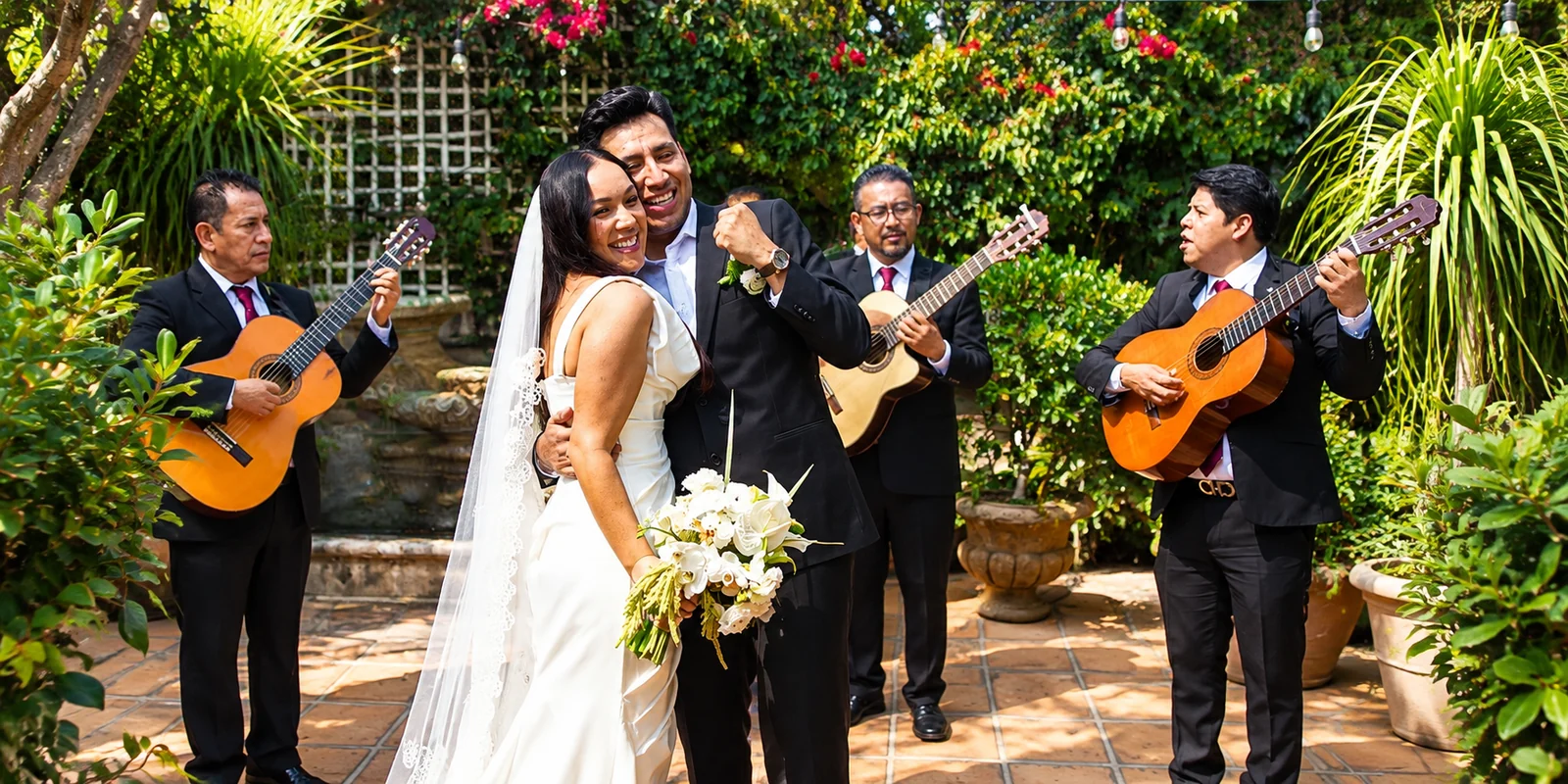 Trío de guitarristas acompañando una celebración al aire libre con invitados